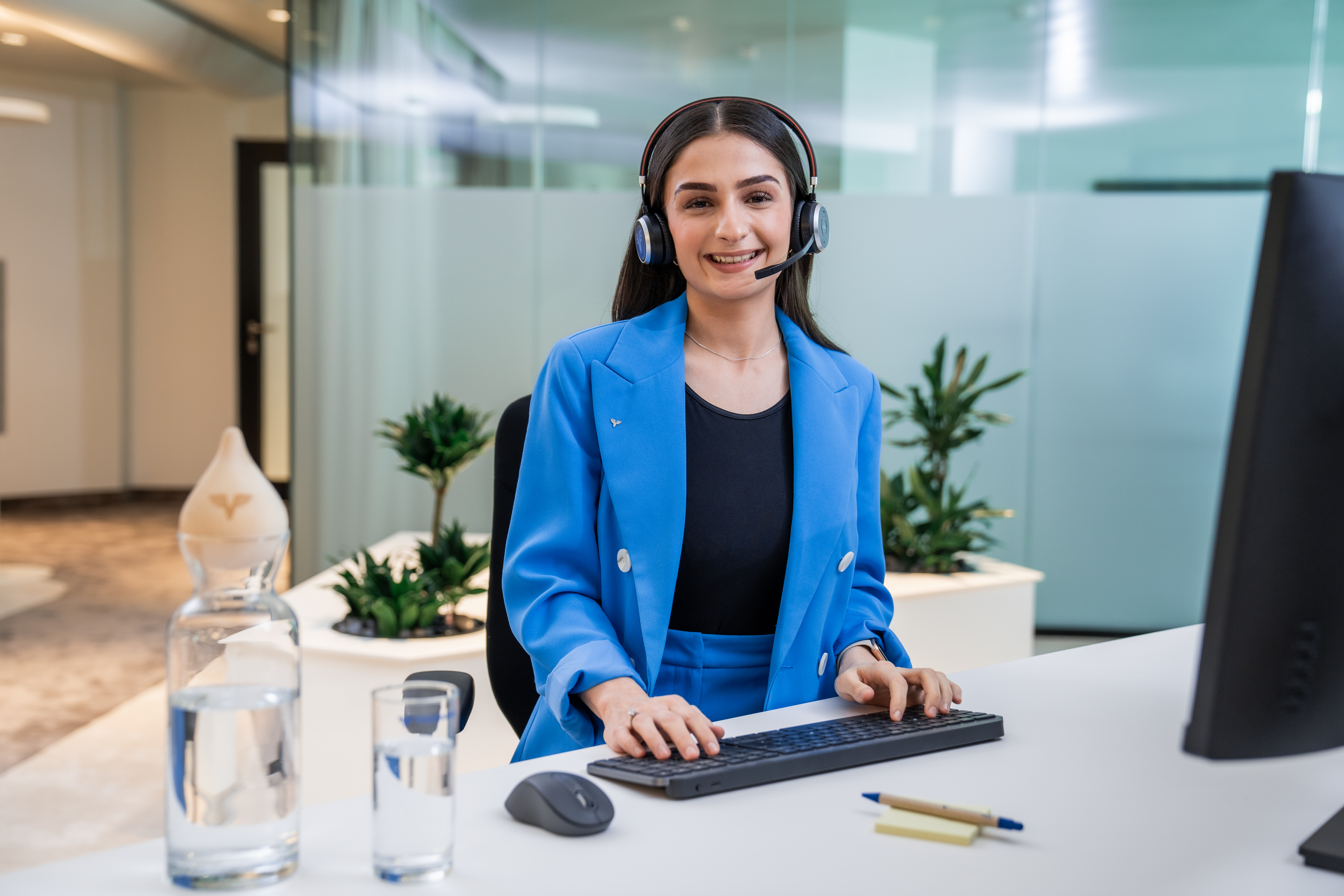 Eine Frau an einem Tisch stehend mit einem Headset und einem Laptop